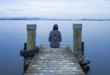 Girl sitting at the end of a pier
